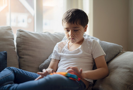 坐着手一个在沙发上快乐的小孩坐在沙发上玩着多色塑胶具在室内画像带