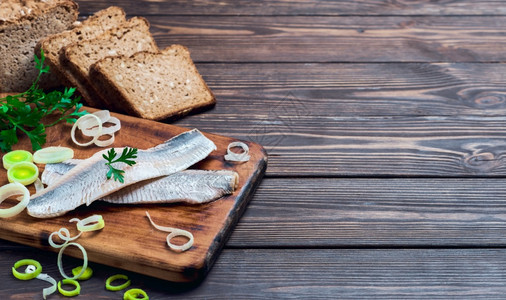 吐司高的鲱鱼片切板上有欧芹和洋葱深色木质背景有文字位置传统挪威或丹麦smorrebrod配料鲱鱼三明治健康食品概念新鲜的图片