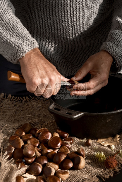 西班牙语奥本人准备栗子用于煎炸有选择地集中注意手和刀的栗子放在一张黑桌子上在圣诞节或假日抽切栗子季节盘关闭秋天图片