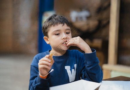 饥饿男孩在吃Churros棒学校儿童在咖啡厅午餐后吃零食健康儿童坐在咖啡店吃饭甜点请享用夏天图片