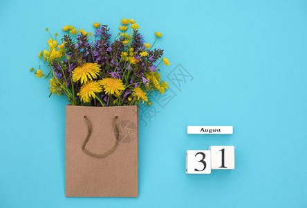 8月31日的Wooden立方体日历8月31蓝背景的工艺品包中野外多彩生鲜花蓝色背景的GreetingcardFlatLayCon图片