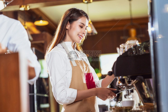女职业亚洲酒吧准备咖啡加拿铁或卡布奇诺咖啡供店的顾客点菜制咖啡小商业主和咖啡店餐馆的开业概念以及牛奶图片