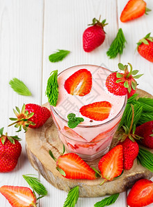 新鲜在木架上玻璃杯中的草莓鸡尾酒白木底的色本草莓和桌边分散的小菜制作饮料粉碎的成分生活牛奶图片