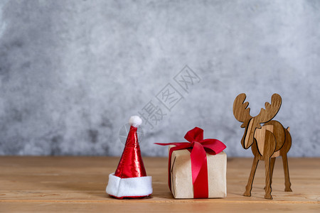 销售欢乐新年装饰品概念吉夫特盒子带有圣塔克拉乌斯帽和驯鹿用具在现代棕褐色绿宝石背景的聚会季节举行晚宴红色的内部图片