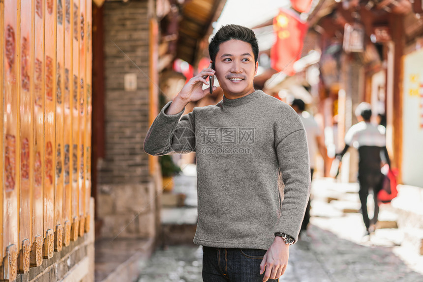 享受利用智能手机拨打利江老城旅行时的电话以友情生活方式和休闲概念为旅行和游提供电话服务并进行友好生活方式和旅游传统的超过图片