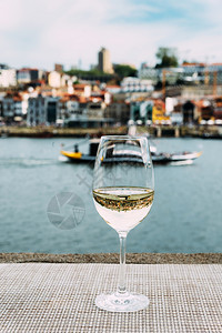 边缘白葡萄酒杯的选择焦点俯瞰葡萄牙波尔图杜罗河上CaisdaRibeira的VilaNovadeGaia堤岸玻璃上的桥反射白葡萄图片