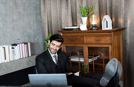 下班后成功放松或睡觉的商人在工作完成后功地放松或睡觉使首席执行长工作人员站立在办公休息时间看电脑屏幕坐在桌子上用双腿坐着的手提电图片