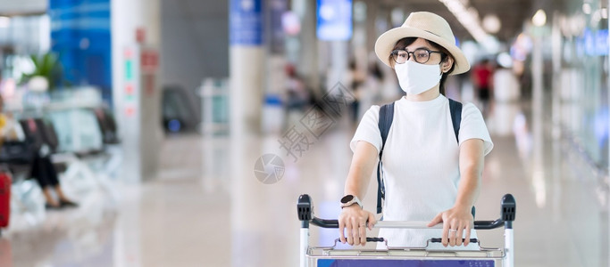 在机场终点站戴面罩保护科罗纳疾感染带帽子的亚洲女旅行家携带李手推车新正常和根据COVID19概念进行的旅年轻成女子社会的亚洲人旅图片