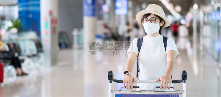 在机场终点站戴面罩保护科罗纳疾感染带帽子的亚洲女旅行家携带李手推车新正常和根据COVID19概念进行的旅年轻成女子社会的亚洲人旅图片