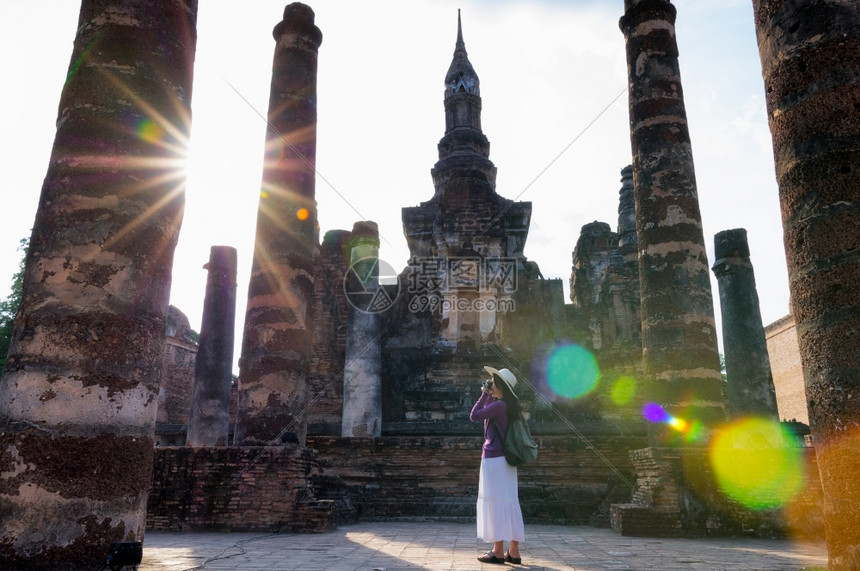 游客亚洲女旅者在WatMaha的Sukhothai历史公园站立并拍摄照片该公园是教科文组织在泰国的世界遗产址有目光耀斑Sukho图片