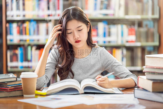 西班牙裔文学的人们亚洲青年学生在大图书馆或群落阅读和做功课书架背景的木制桌子上有各种书本和文具回学校后读书架背景上的各种书籍和文图片