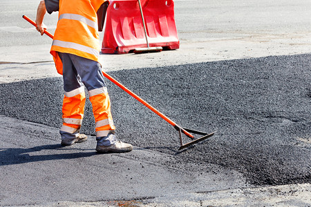 道路服务人员用新鲜的热沥青更一段道路并用金属水平将其滑以进行手动维修道路服务人员在修复道路时用金属水平手动滑热沥青户外灰色的行业图片