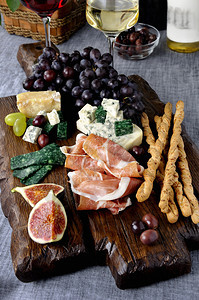 木板上不同种类的奶酪葡萄和无花果子图片