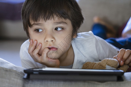 冒险脸关心躺在沙发上玩游戏家庭教育社交距离电子学习在线教育的波尔德男孩在沙发网上教育等方面图片