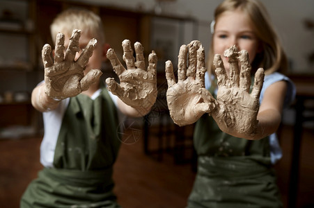 孩子们用粘土展示双手在艺术学校上讲课的孩子们手在泥土中展示双手青年工艺大师爱好者快乐童年儿用泥土展示双手成型制造雕塑家图片