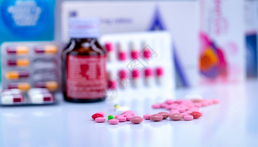 模糊药瓶上的片剂和胶囊丸泡罩包装中的胶囊和药物纸盒包装上的粉红色和片剂药房柜台上的绿黄色胶囊制药业绿色抗生素药品图片