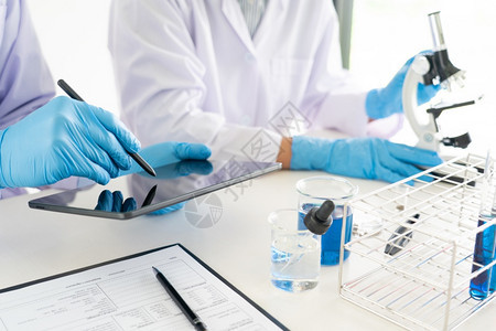 关心脱氧核糖酸审判参加实验室大衣和安全护目镜的有吸引力年轻科学家小组利用实验室中的测试管分析验或调查在实室中分析试或调查图片