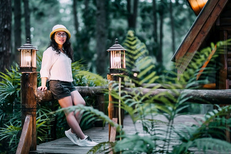 在泰国清迈县DoiBoLuang森林公园自然足迹上的松树林木小屋绿中身着白衣戴帽子的亚洲女观光游客站立在松树小屋内秋天肖像绿色图片