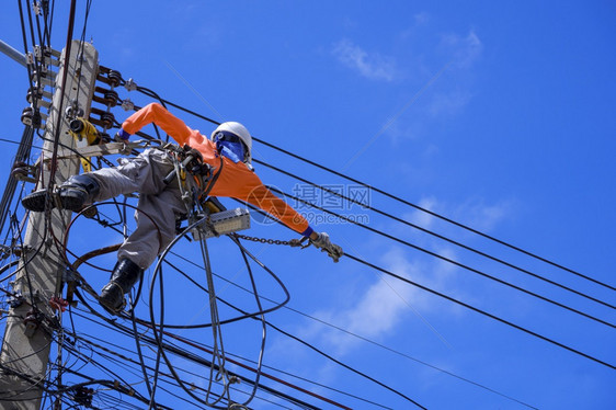 技术员泰国低角度观测带安全设备和各种工作具的电动器低角度视图在蓝色天空背景下安装电缆线和杆上源系统人们图片