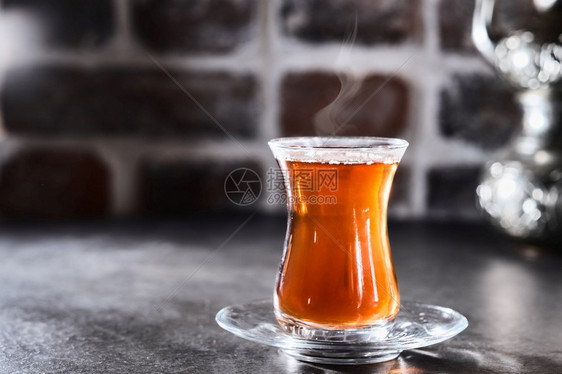 阿塞拜疆土耳其红芳香茶在传统玻璃杯中深砖底面的铁板蒸汽车在茶杯上方升起近距离浅深度田间复制空早餐东方的图片