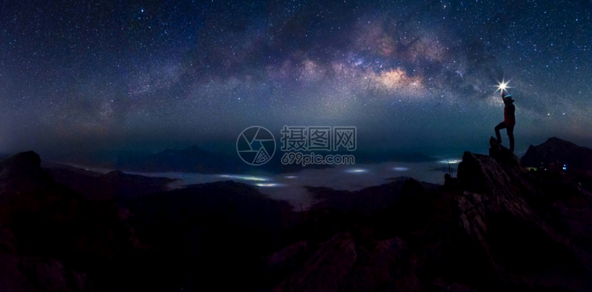 自然多岩石的登山者或背包全景轮的他将光照高举在头顶上站岩石山峰和银河系上成功胜利获领先导概念高等与噪音领袖在上面男人图片