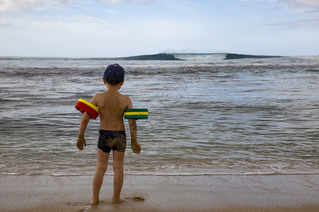 滑稽小男孩在沙滩上有水翼等待滚动波浪的到来测试量图片