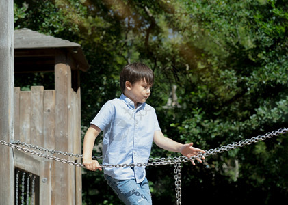 乐趣活跃的小孩在游乐场上拿着金属链享受户外活动的儿童在日夏阳光明媚的冒险公园中攀爬绳链里玩游戏混合种族小男孩在学校游乐场玩耍自然图片