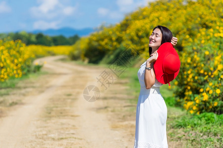 南邦红色的一位身着白裙子戴红帽的美丽女在一条农村公路上春光时戴着红帽墨西哥向日葵田MeeMohCoalMine自然图片
