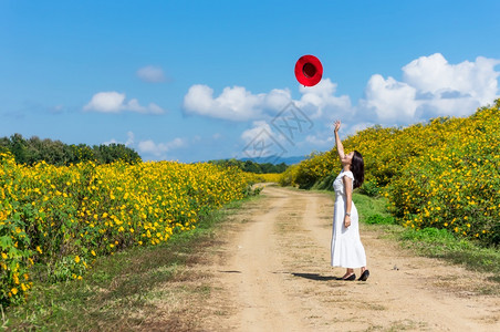一位身着白裙子戴红帽的美丽女在一条农村公路上春光时戴着红帽墨西哥向日葵田MeeMohCoalMine女孩季节放松图片