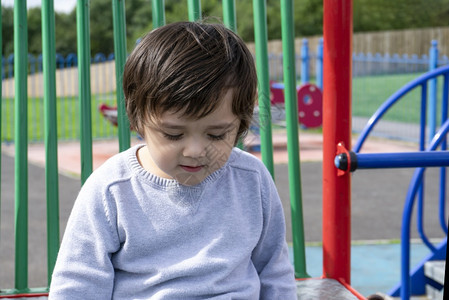 明亮的孩子在游乐场独自玩的肖像男孩CandidChild指向下看在阳光明媚的夏日学校户外地区玩耍托德勒男孩晴天图片