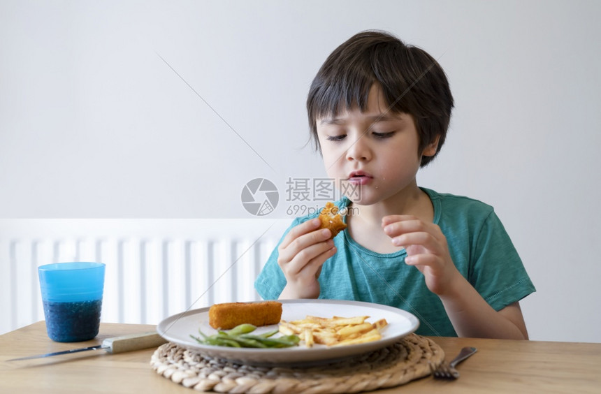 家庭5岁男孩的肖像在家吃周日晚饭时有自制鱼手指和薯条一个快乐的孩子吃午餐儿童热菜和新鲜食品健康生活方式概念健康生活方式戳食谱图片