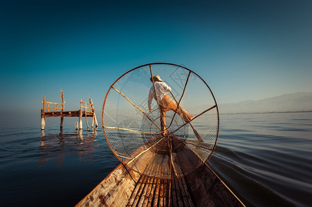缅甸河旅行目的地缅甸竹船上渔夫以传统方式与手工制作的Inle网湖捕鱼使用手工制造的Inle湖缅甸旅游目的地捕捉缅甸语著名的图片