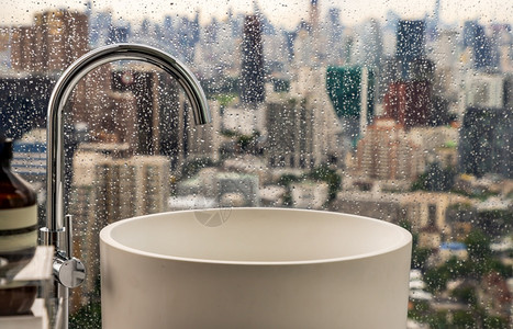 窗户城市景观天空现代卫生手盆有城市风景可以从大窗外看面的雨天特优水龙头和部件卫生防护网保健概念有选择的重点图片