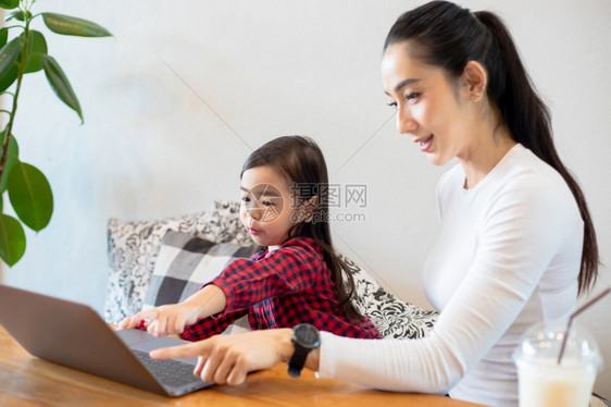 在职的成人活亚洲母亲正在教女儿阅读一本书并使用笔记本和技术在家庭学校放假期间进行网上学习教育概念和家庭活动教育概念与家庭活动利用图片