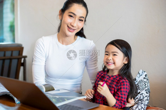 女亚洲人他们的母亲正在教女儿阅读一本书并使用笔记本和技术在家庭学校放假期间进行网上学习教育概念和家庭活动教育概念与家庭活动利用笔图片