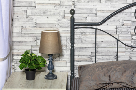 内部的架子床棕色调一个绿花盆张优雅的旧桌灯在床边子上与旧木板灰墙的保持良好平静的面条风格和卧室头板的内部以木板为背景而卧室的头板图片