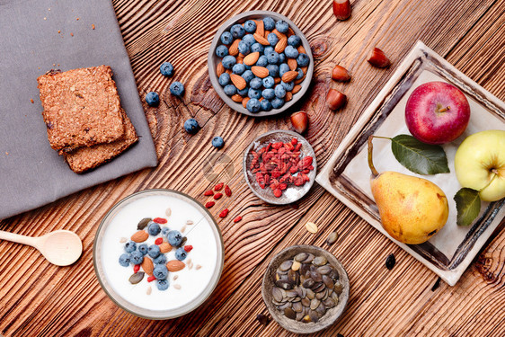 混合均衡在桌边吃酸果早餐加上蓝莓和烤杏仁木制桌面上的米斯里饼干苹果和梨子灯光健康膳食优质平衡饮自上而下木制的图片
