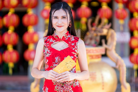 运气身着红色传统青山装饰的亚洲年轻女子肖像挂着黄信封上面写着中文字祝福是新年庆典的幸运日普通话庆祝图片