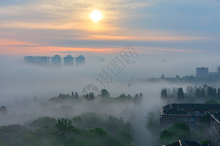 蒙清晨一阵浓雾像黄昏一样在城市公园的房屋和树木之间蔓延在太阳升起的柔软触碰下清晨升起的阳光照亮了轻地唤醒沉睡的城市笼罩着浓雾就像图片