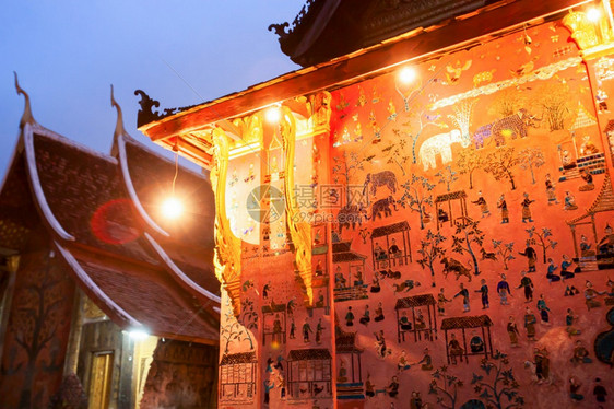 著名的日落文化黄昏时美丽的香通寺古庙温暖的灯光照在墙上彩色玻璃背景是蓝天老挝琅勃拉邦这座寺庙对公众开放图片