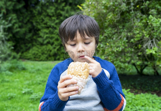 户外吃汉堡的小男孩图片