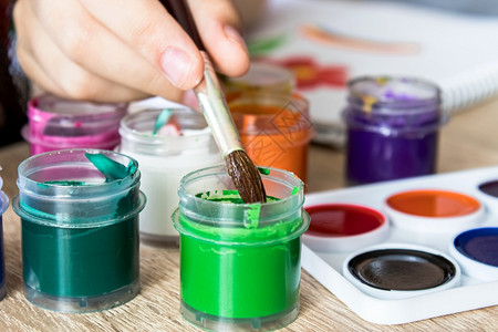 创造力孩子的手握着刷用于绘画和从一个罐子里捡起古阿切为儿童提供娱乐活动更接近儿童孩子的手握着一把刷子用于从一个罐里画起和拾古阿丘图片