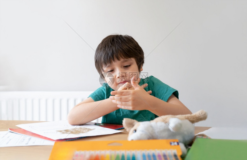 保持学校在家工作独自做功课的学童肖像男孩拿着棕色笔画和在白纸上写桌子小学和家庭教育概念上的白纸写作图片
