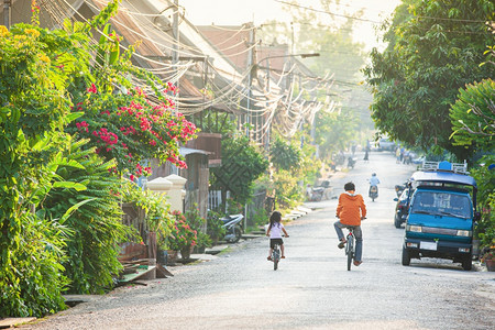 车辆人们温暖的老挝父亲和女儿在晚上的小巷骑自行车在北老挝LuangPrabang教科文组织非物质化遗产选择重点运动模糊不清的鲁昂图片