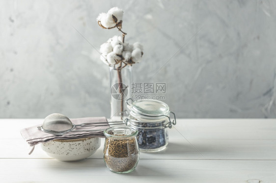 液体内部的现代咖啡豆和玻璃罐中的即时咖啡棉花和白色木桌的餐具面壁为灰水泥墙背景是灰色混凝土的白木板上茶瓷家庭内Cosy概念中的死图片