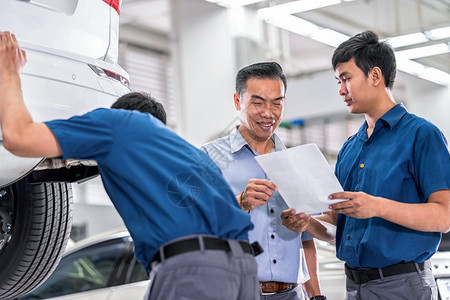 专家亚洲机械师向客户介绍维修服务中心的工作这是展厅汽车修理和工作概念协议的一部分亚洲机械师就维修服务向客户讲述并展示了有关工作顾图片
