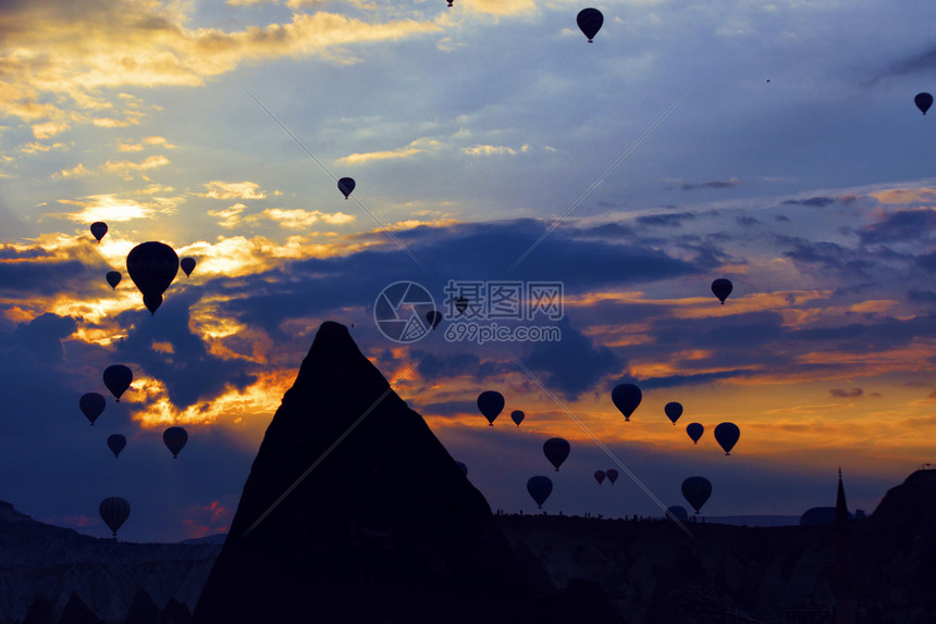 谷在土耳其中部卡帕多西亚锥形悬崖上日出和蓝天照亮的背景下在清晨的背光下对几十个飞气球的清晰可见景象吸引数十个气球攀爬到卡帕多西亚图片