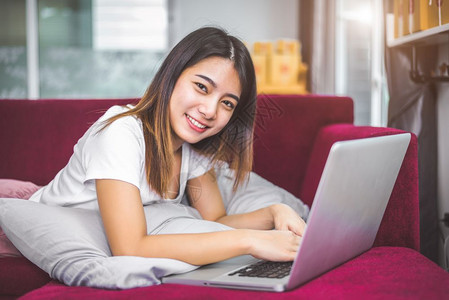年轻女在红沙发上用笔记本电脑在互联网上浏览红沙发充满欢乐的手感情绪销售和在线购物概念商机和营销新人企业家的幸福手势电子商务在室内图片