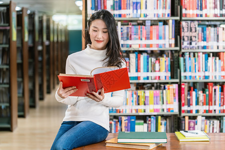后退年轻的日本人在大学图书馆读的亚洲青年学生或者在书架背景的木制桌子上读书的合唱团回学校概念缩写BacktoschoolUniv图片