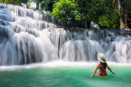 身穿粉红白色帽子站在美丽的瀑布中放松水女士们在泰国SangkhlaburiKanchanaburi省Noppiboon瀑布上站立图片